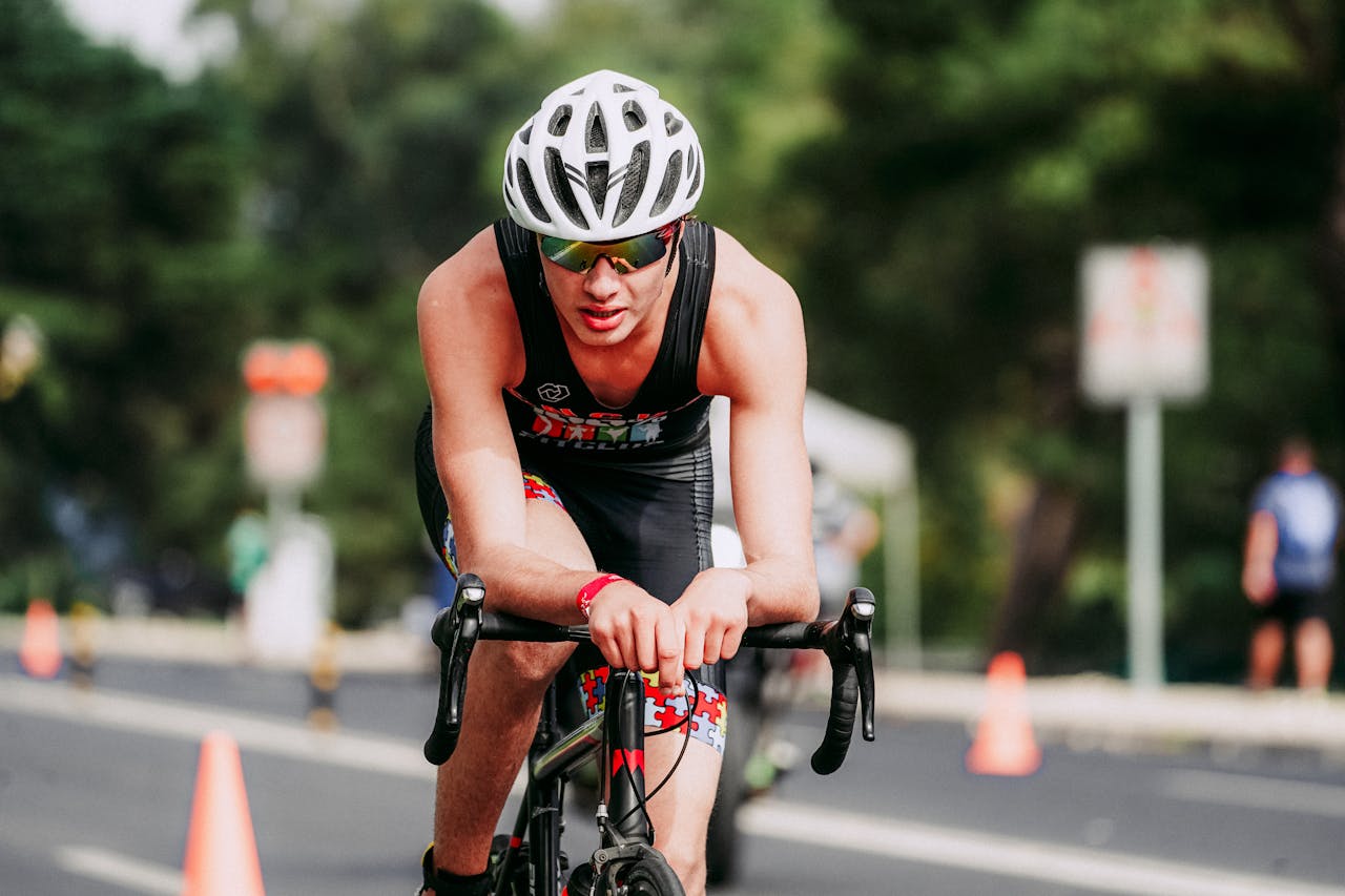Unrecognizable sportsman in helmet and sportswear and sunglasses participating in cycling competitions in city in daytime